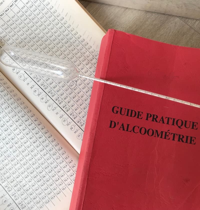 Guide pratique d'alcoométrie et alcoomètre posés sur les tables de conversion.